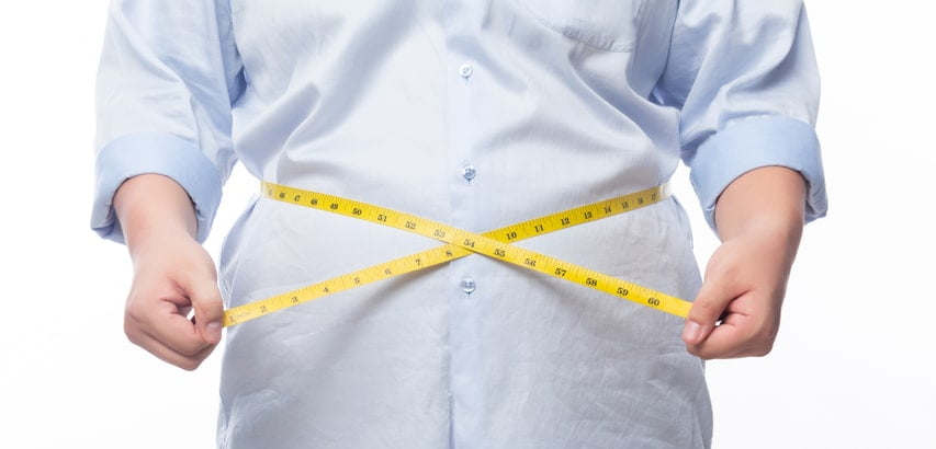 A man in a light blue shirt holds a yellow measuring tape around his waistline.