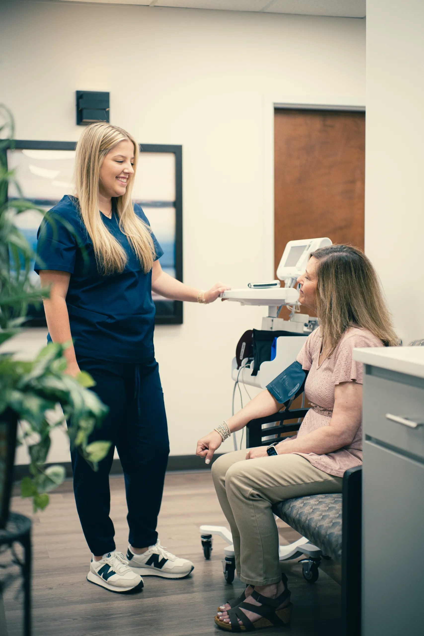 Nurse checking a patient's blood pressure with a digital monitor in a medical clinic, friendly staff interaction