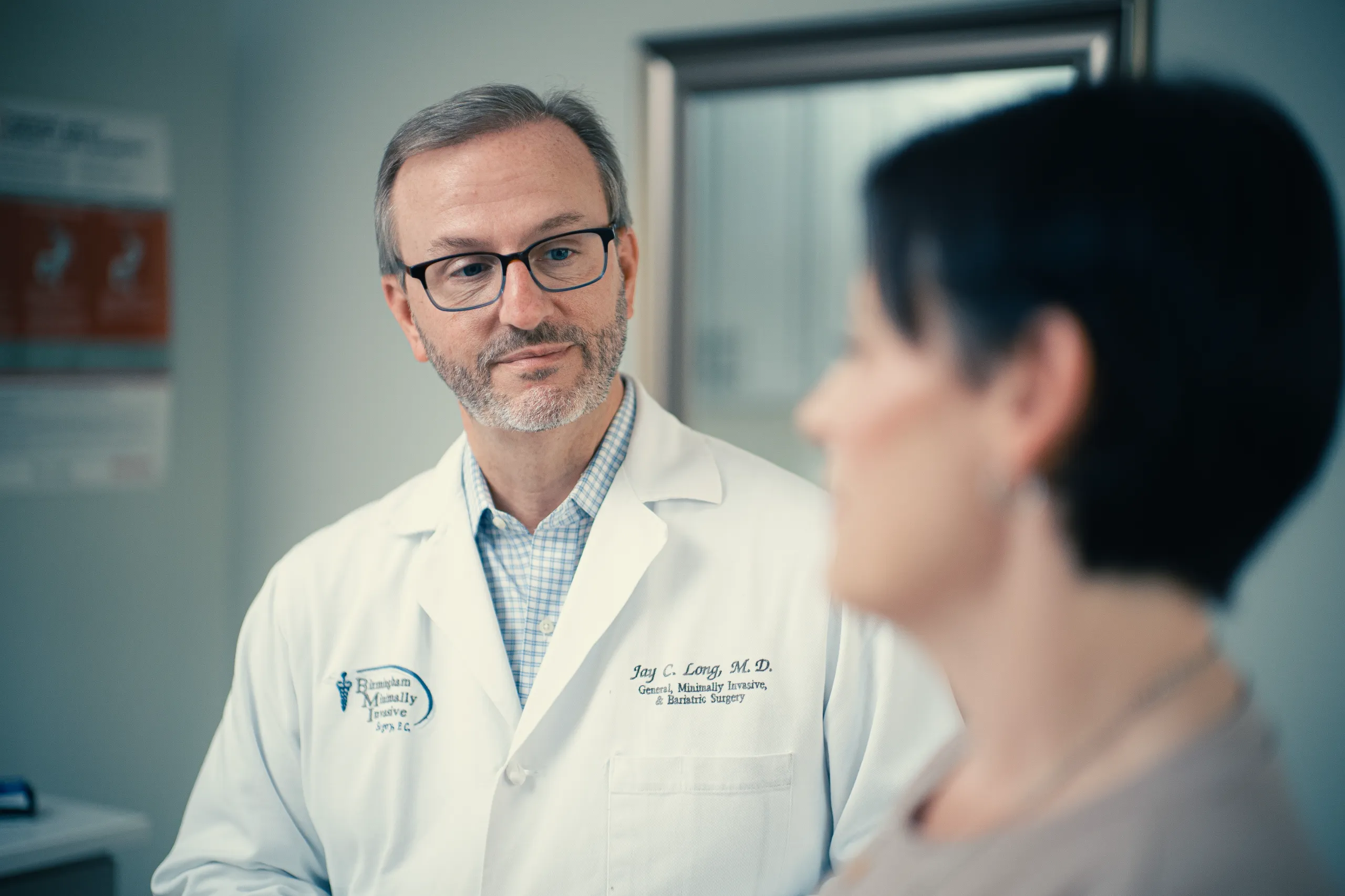 Male doctor in white coat consulting a patient in a clinic, wearing glasses with a caring expression